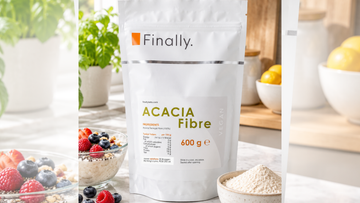 Finally. Acacia Fibre 600g pouch beside a bowl of berries and a small bowl of fibre powder on a kitchen counter.