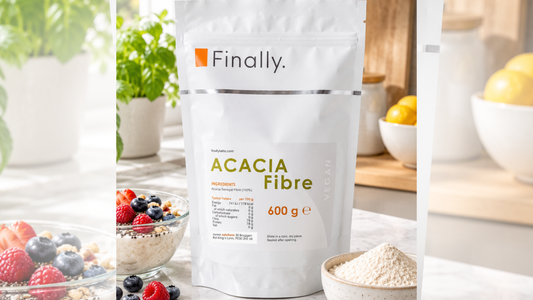 Finally. Acacia Fibre 600g pouch beside a bowl of berries and a small bowl of fibre powder on a kitchen counter.