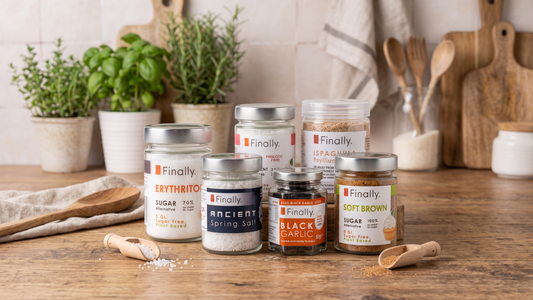 Finally Keto pantry essentials on a wooden kitchen worktop: erythritol, Soft Brown, black garlic, Ancient Spring Salt, prebiotic fibre and psyllium husks.