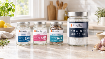 Finally. coarse, fine and black garlic spring salt jars beside a larger Ancient Spring Salt jar on a kitchen worktop.